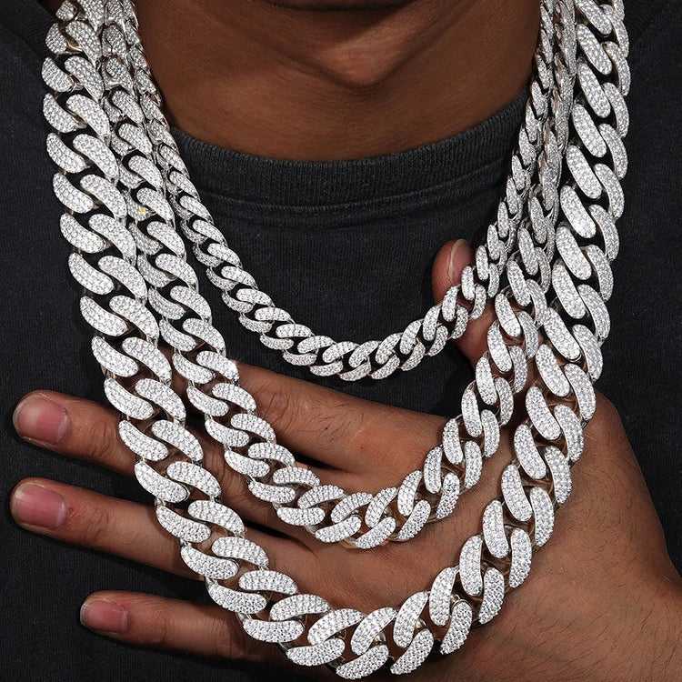 A close-up of a person wearing a thick, multi-strand silver Cuban link chain necklace covered in sparkling stones