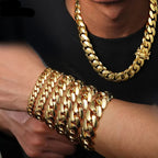 A close-up of a person wearing a thick gold Cuban link chain necklace and matching stacked gold chain bracelets on the wrist, with a black shirt visible.