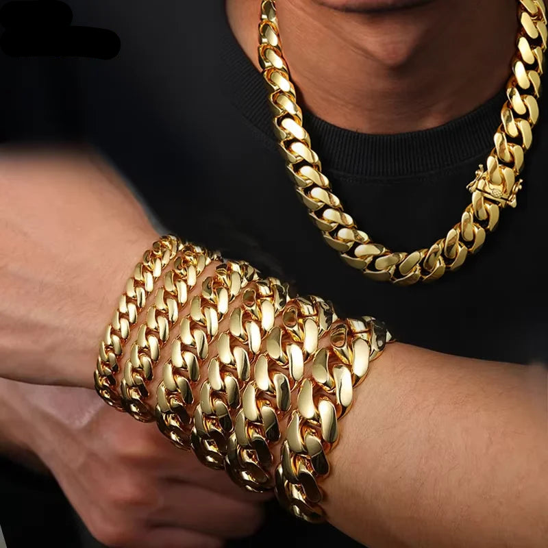 A close-up of a person wearing a thick gold Cuban link chain necklace and matching stacked gold chain bracelets on the wrist, with a black shirt visible.