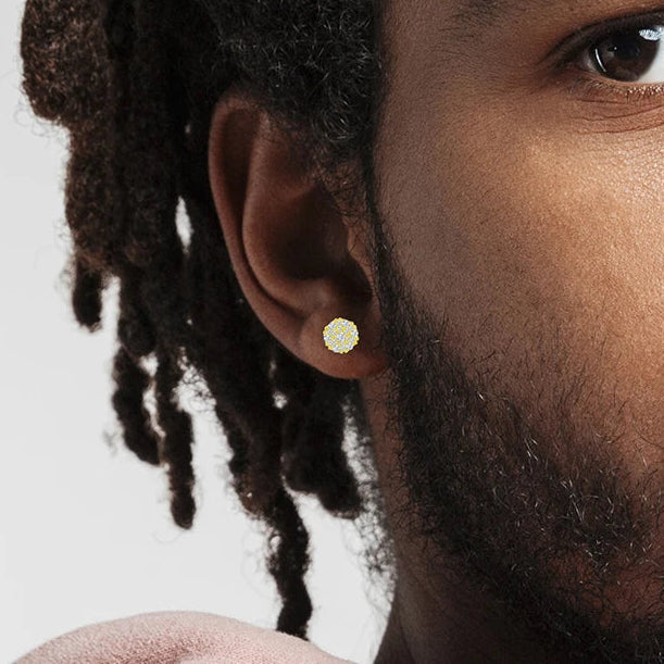 Close-up of a person wearing a gold earring with a plain background