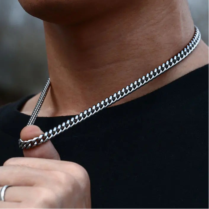 Person wearing a silver chain necklace with a blurred background